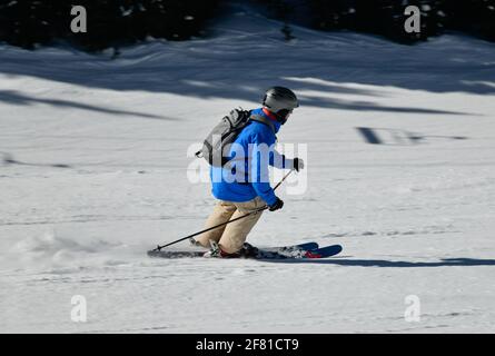 Skieur descendant les pistes à grande vitesse par temps ensoleillé avec spectacle frais à la station de ski de Vail, Colorado Banque D'Images