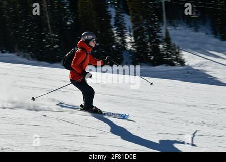 Skieur descendant les pistes à grande vitesse par temps ensoleillé avec spectacle frais à la station de ski de Vail, Colorado Banque D'Images