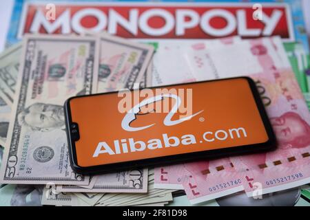 Alibaba logo vu sur smartphone qui est placé sur l'argent - dollars américains et yuan chinois, et le jeu de monopole sur le fond flou. Concept. Staffrod Banque D'Images