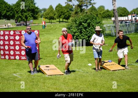 Les hommes et les femmes jouent au jeu de sac de haricots lors de l'événement du week-end au doré jaune au parc au bord du lac pendant qu'une communauté se réunit. Banque D'Images