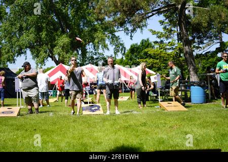 Les hommes et les femmes jouent au jeu de sac de haricots lors de l'événement du week-end au doré jaune au parc au bord du lac pendant qu'une communauté se réunit. Banque D'Images