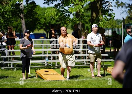 Les hommes et les femmes jouent au jeu de sac de haricots lors de l'événement du week-end au doré jaune au parc au bord du lac pendant qu'une communauté se réunit. Banque D'Images