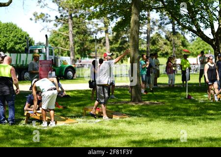 Les hommes et les femmes jouent au jeu de sac de haricots lors de l'événement du week-end au doré jaune au parc au bord du lac pendant qu'une communauté se réunit. Banque D'Images