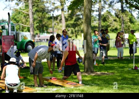 Les hommes et les femmes jouent au jeu de sac de haricots lors de l'événement du week-end au doré jaune au parc au bord du lac pendant qu'une communauté se réunit. Banque D'Images