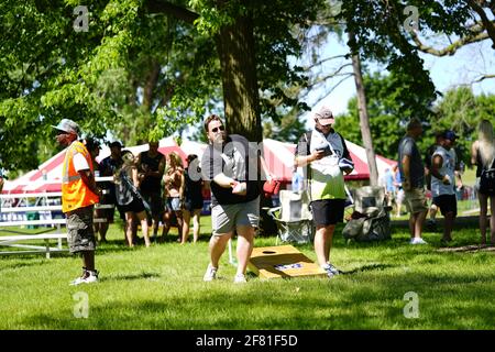 Les hommes et les femmes jouent au jeu de sac de haricots lors de l'événement du week-end au doré jaune au parc au bord du lac pendant qu'une communauté se réunit. Banque D'Images