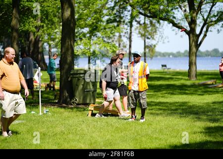 Les hommes et les femmes jouent au jeu de sac de haricots lors de l'événement du week-end au doré jaune au parc au bord du lac pendant qu'une communauté se réunit. Banque D'Images