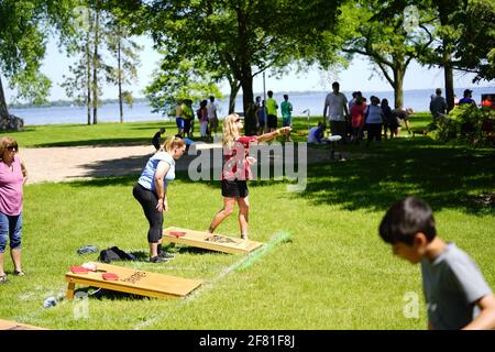 Les hommes et les femmes jouent au jeu de sac de haricots lors de l'événement du week-end au doré jaune au parc au bord du lac pendant qu'une communauté se réunit. Banque D'Images