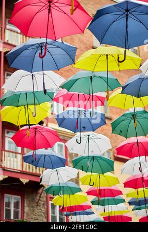 Variété de parasols jaunes, rouges, bleus, roses et blancs suspendus au-dessus d'une rue au Québec, Canada Banque D'Images
