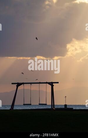 Silhouette de balançoire en bois avec beau coucher de soleil sur la colline près de la mer Banque D'Images