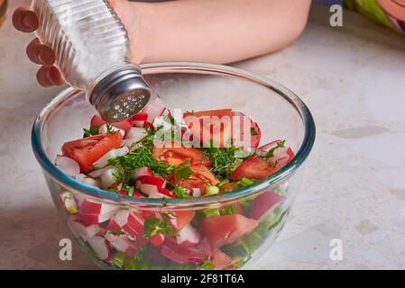 salez la salade avec les légumes dans une assiette Banque D'Images