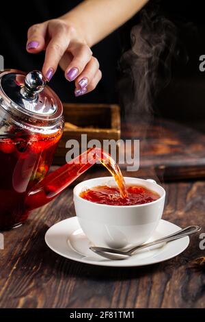 Femme mains versant le thé chaud dans une tasse de la casserole Banque D'Images