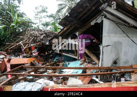 East Java, Indonésie. 11 avril 2021. (Un garçon quitte une maison endommagée après qu'un séisme de magnitude 6.1 ait frappé le village de Kali Uling à Lumajang, Java-est, Indonésie, le 11 avril 2021. Six personnes ont été tuées, une autre grièvement blessée et des dizaines de bâtiments ont été endommagés après un séisme de magnitude 6.1 qui a secoué samedi la province orientale de Java en Indonésie, à l'ouest de l'île, a déclaré les responsables. Le tremblement de terre a frappé à 14 heures crédit: Xinhua/Alamy Live News Banque D'Images