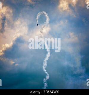 Affichage de l'antenne Airshow. Un seul avion effectuant des acrobaties aériennes avec un sentier de fumée sur fond de ciel sombre. Banque D'Images