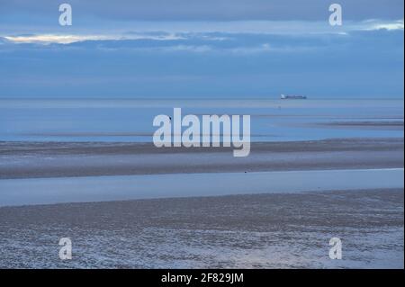 Belle vue en soirée de Blackrock Beach à marée basse, seul homme à marcher et cargo en arrière-plan, Dublin, Irlande Banque D'Images