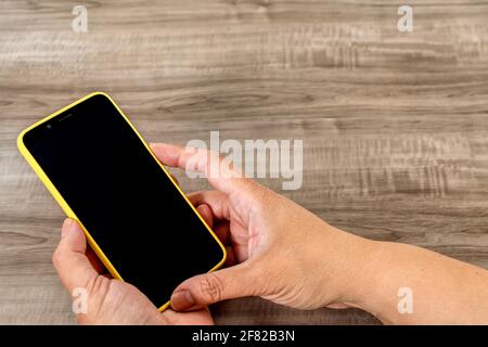 Vue de dessus des mains qui tiennent un téléphone cellulaire une table en bois Banque D'Images