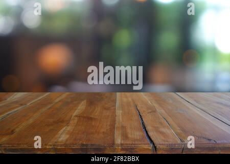 Table en bois vide devant un café flou abstrait, restaurant la nuit. Pour l'affichage de produit de montage ou la mise en page visuelle clé de conception - image Banque D'Images
