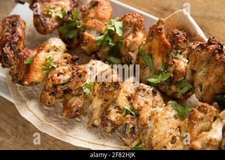 Les ailes de poulet britanniques qui ont été marinés dans les épices marocaines de Ras el Hanout avant d'être brochées et grillées à la maison. Angleterre GB Banque D'Images