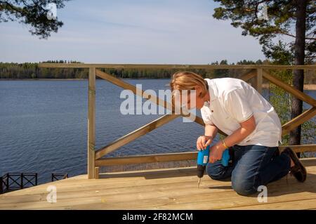 Un homme avec un tournevis fixant des planches sur un pont en bois Banque D'Images