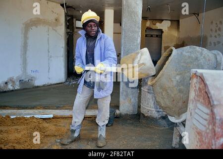 Un ouvrier de construction noir mélangeant du ciment Banque D'Images