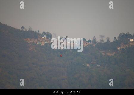 Katmandou, Népal. 11 avril 2021. Un hélicoptère de la compagnie Simrik Airlines serra un feu de forêt qui a flambé le long de la forêt de Shivapuri à Katmandou, au Népal, le dimanche 11 avril 2021. Crédit: Skanda Gautam/ZUMA Wire/Alay Live News Banque D'Images