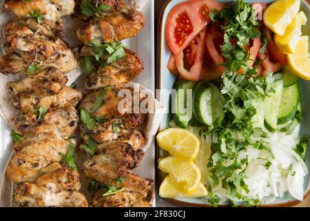 Les ailes de poulet britanniques qui ont été marinés dans les épices marocaines de Ras el Hanout avant d'être brochées et grillées à la maison. Servi avec une coriandre, on Banque D'Images