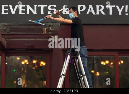 Pékin, Chine. 11 avril 2021. Un membre du personnel chinois porte un masque de protection tout en nettoyant l'extérieur d'un bar occidental populaire, entièrement ouvert pour les affaires, à Beijing le dimanche 11 avril 2021. La capitale chinoise a réduit le port obligatoire de masques protecteurs, sauf dans les transports en commun, et les distances sociales à mesure que la ville retourne lentement à la vie pré-covid 19 avec des restaurants, des entreprises et des écoles entièrement ouverts. Photo de Stephen Shaver/UPI crédit: UPI/Alay Live News Banque D'Images