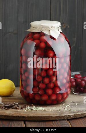 Compote de cerises sucrées en conserve dans un pot en plastique libre sur fond de garde-manger rustique en bois, gros plan, solution de stockage des aliments, produits en conserve, cuisson par lots, s Banque D'Images