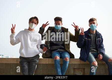 Un gros plan de trois jeunes Caucasiens heureux et les Hispaniques gars port de masques sanitaires à l'extérieur Banque D'Images