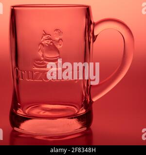 Cruzcampo bière mug dans un cadre de studio avec un fond rouge de couleur rouge. Cruzcampo est la bière la plus consommée en Espagne Banque D'Images