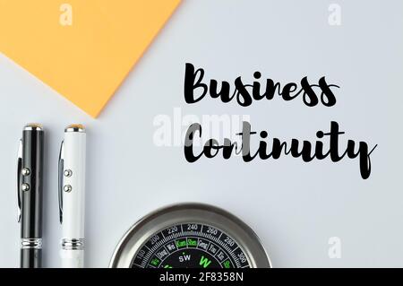 Stylo, boussole et ordinateur portable sur fond blanc écrit avec LA CONTINUITÉ DE L'ACTIVITÉ Banque D'Images
