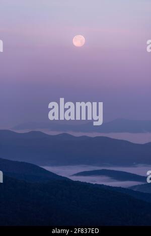 Couleurs pastel sur les vallées brumeuses du parc national de Shenandoah tandis que la pleine lune se couche pendant un lever de soleil d'été. Banque D'Images