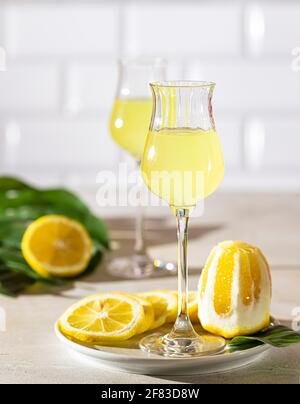 Limoncello, liqueur italienne traditionnelle sur fond de béton léger aux rayons du soleil. À côté, il y a un citron jaune, des agrumes frais. Sélection Banque D'Images