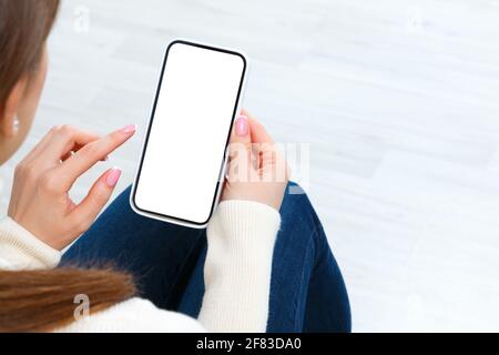 Vue arrière d'une fille tenant un smartphone avec une maquette blanche d'écran vierge. Concept de style de vie avec technologie numérique. Banque D'Images