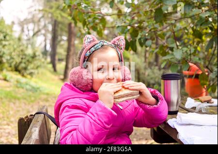 Petite fille sur un pique-nique. Les enfants mangent des toasts et des boissons dans le parc lors d'un pique-nique au printemps. Journée en famille dans la nature. Photo de haute qualité Banque D'Images