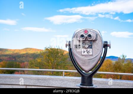 Gros plan de jumelles à pièces faisant face à des montagnes boisées à le pic des couleurs de l'automne lors d'une journée d'automne claire Banque D'Images