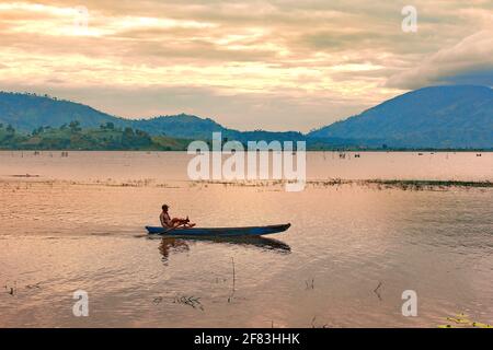 Homme sur un petit bateau en bois flottant sur le lac le paysage du matin Banque D'Images