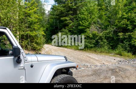 Voiture argent avec de grandes roues sur une route de terre dedans l'été avec des arbres autour Banque D'Images