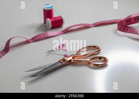 fil en ciseaux et ruban de mesure sur une surface blanche Banque D'Images