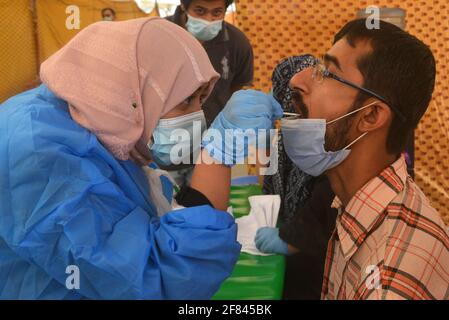 Lahore, Pakistan. 11 avril 2021. Un agent de santé pakistanais recueille un échantillon d'écouvillonnage auprès d'un citoyen de Ramzan Sasta Bazar alors que les gens viennent acheter une épicerie dans la ville de Shalamar dans le cadre du paquet de secours du Ramadan organisé par le gouvernement provincial avant le mois Saint des musulmans de Ramzan-ul-mubarak à Lahore. (Photo de Rana Sajid Hussain/Pacific Press) Credit: Pacific Press Media production Corp./Alay Live News Banque D'Images