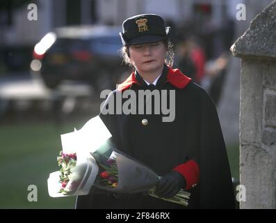 Un gardien du château porte un bouquet de fleurs au château de Windsor, dans le Berkshire, à la suite de l'annonce de la mort du duc d'Édimbourg, le vendredi 9 avril, à l'âge de 99 ans. Date de la photo: Dimanche 11 avril 2021. Banque D'Images