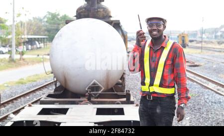 Homme africain ingénieur tenant la communication radio ou talkie walkie et debout dans le train Banque D'Images