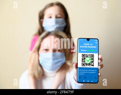 Passeport sanitaire de la vaccination COVID-19 dans téléphone mobile, femme heureuse et enfant tenir smartphone avec application de certificat de vaccination, coronavirus numérique Banque D'Images