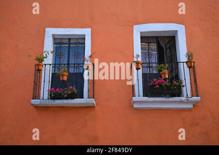 Façade de maison coloniale avec un mur en stuc vénitien, bordure blanche autour des fenêtres et balustrades de balcon en fer artisanal à Cholula, Puebla Mexique. Banque D'Images