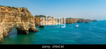 Vue sur la falaise de rochers de grès escarpé, formations rocheuses et arches rocheuses dans la mer turquoise, plage de sable sur la falaise, Praia da Marinha, Algarve Banque D'Images