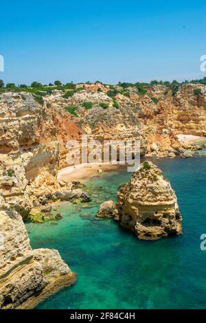 Vue sur la falaise de rochers de grès escarpé, formations rocheuses dans la mer turquoise, plage de sable, Praia da Marinha, Algarve, Lagos, Portugal Banque D'Images