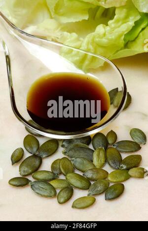 Graines de citrouille, huile de graines de citrouille dans une cuillère à salade (Cucurbita pepo var. Styriaca) Banque D'Images