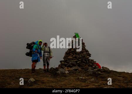 Les touristes en imperméable se tiennent sur le sommet de la montagne, le Mont Bebeneskul et le brouillard, les nuages de pluie sur la crête monténégrine, les touristes heureux.2020 Banque D'Images