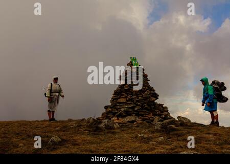 Les touristes en imperméable se tiennent sur le sommet de la montagne, le Mont Bebeneskul et le brouillard, les nuages de pluie sur la crête monténégrine, les touristes heureux.2020 Banque D'Images