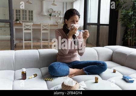 Malade jeune femme lutte contre la fièvre mesurer la température prendre des médicaments Banque D'Images