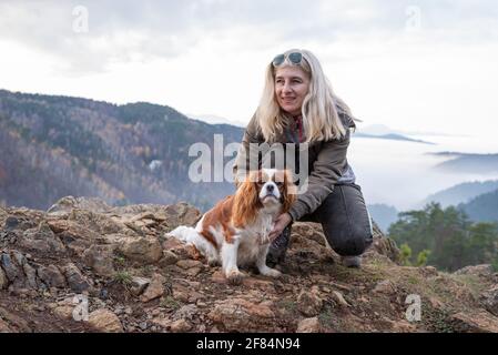 Blonde femme et son cavalier roi charles spaniel sur un sommet de la montagne par une journée brumeuse Banque D'Images